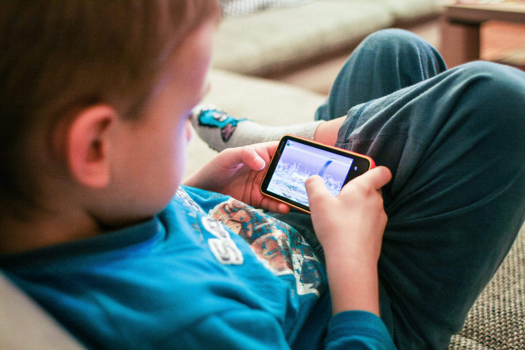 ways to raise generous children - kid plays game on phone